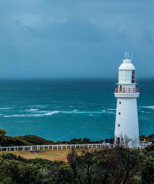 A white lighthouse beacon at the coast of the ocean